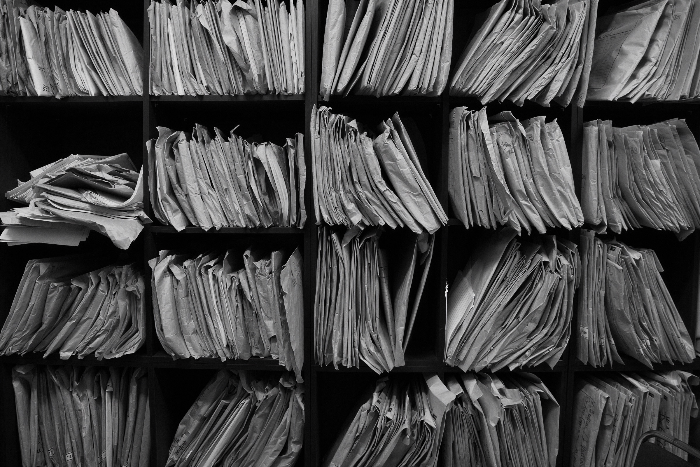 Archivero lleno de expedientes de papel apilados en repisas
