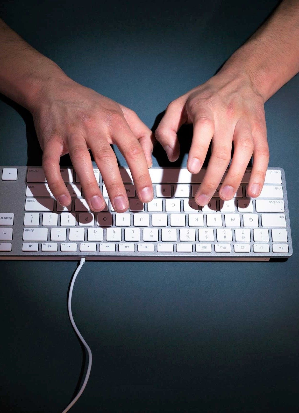 Manos escribiendo en un teclado, vistas desde arriba